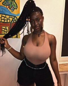 Curvy Afro-Caribbean woman in a halter top with long braided hair posing confidently – adult phone chat model in London.