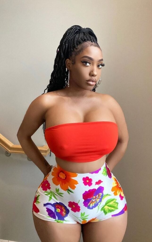 Busty Caribbean woman in a red tube top and floral shorts – seductive adult phone chat girl in Nottingham, UK.