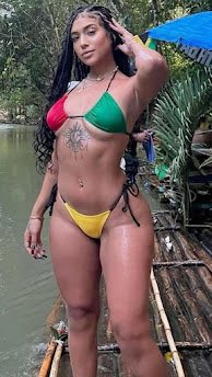 Curvy Jamaican woman in Rasta bikini posing by river, braided hair, tattooed belly, tropical fantasy adult chat model – Kiana Riddim, UK