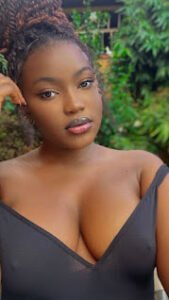Busty African woman with braided hair in a black outfit posing confidently outdoors — Imani Rae, adult phone chat girl UK