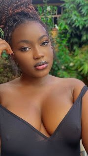Busty African woman with braided hair in a black outfit posing confidently outdoors — Imani Rae, adult phone chat girl UK