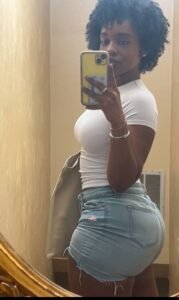 Curvy Caribbean woman in white top and denim shorts taking mirror selfie – adult phone chat in Birmingham.