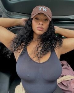 Curvy Afro-Caribbean woman in black tank top posing confidently with hat – Kali Monroe
