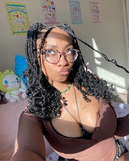 Busty girl with glasses and curly braids in low-cut top, making kissy face in bright room with plushies – Mochi Rae, UK nerdy adult chat girl