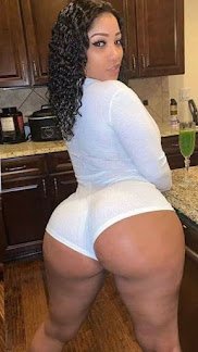 Curvy Latina woman in tight white outfit posing in kitchen, looking back over shoulder – Carmen Luxe, thick UK adult phone chat companion
