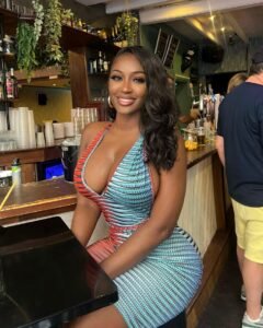 Curvy Afro-Caribbean woman in colorful bodycon dress sitting at a tropical bar – Sasha Divine