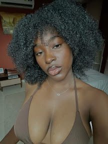 Curvy Black woman with natural afro and deep stare, wearing a brown halter bikini top – Nadira Moon, UK sensual phone chat fantasy girl