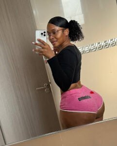 Curvy woman in pink Puma shorts and black crop top taking mirror selfie, turned back pose showing her booty – Nyla Rush, UK adult phone chat tease