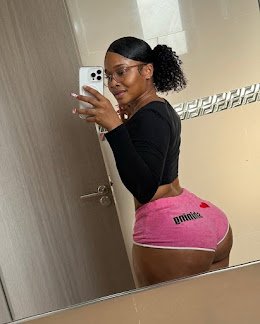 Curvy woman in pink Puma shorts and black crop top taking mirror selfie, turned back pose showing her booty – Nyla Rush, UK adult phone chat tease