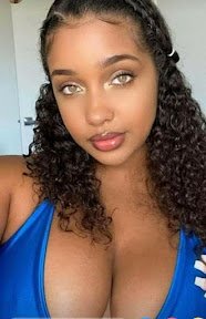 Close-up of beautiful Caribbean woman with hazel eyes and curly hair in a blue top — Sasha Moon, adult phone chat girl in UK
