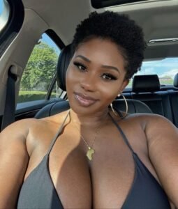 Amara Jewel – busty Afro-Caribbean beauty smiling in a car wearing a black bikini top