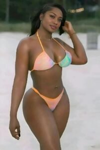 Barbadian beauty Kiara Breeze in a pastel bikini, walking along the beach with a confident smile and sultry gaze.