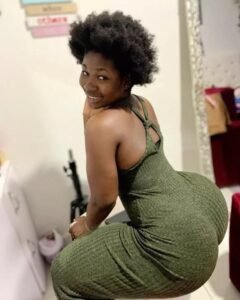 Caribbean beauty Amaia Bliss with natural afro hair, wearing a green dress and giving an over-the-shoulder smile.