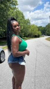 Tiana Blaze – curvy Caribbean woman in green top and denim shorts posing seductively outdoors in Birmingham UK