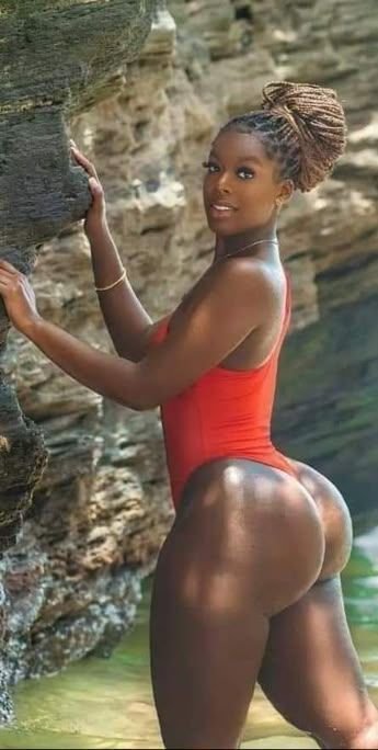 Imani Rose – Curvy Caribbean woman in red swimsuit posing seductively by the rocks in Manchester UK