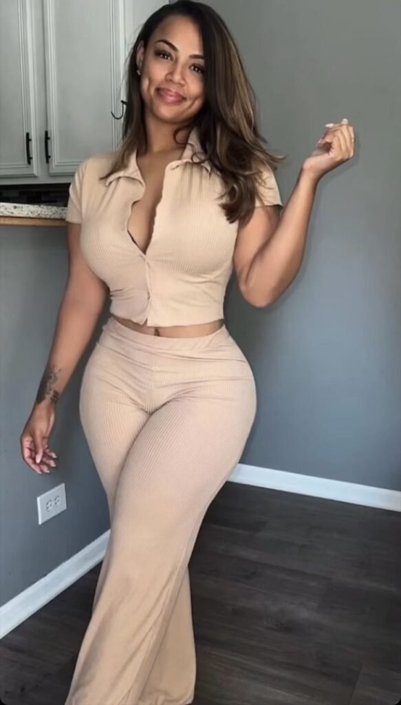 Curvy brunette woman in beige outfit posing with a seductive smile