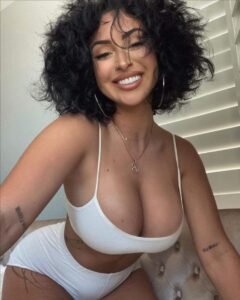 Caribbean woman in white two-piece smiling seductively in London UK