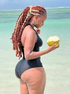 Marisha Dread – Caribbean ebony queen in black swimsuit with coconut by the beach