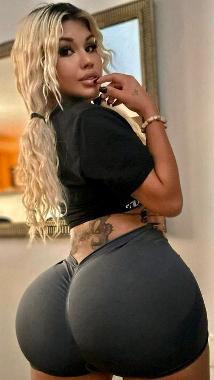 Latina bombshell in black crop top and shorts posing indoors