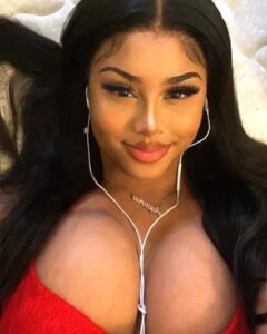 Ebony beauty in red top wearing earphones smiling seductively