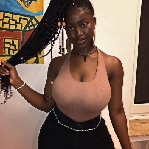 Curvy Afro-Caribbean woman in a halter top with long braided hair posing confidently – adult phone chat model in London.