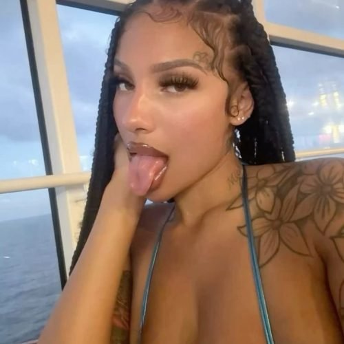 Tattooed British woman in braided hair teasing with tongue on a boat – Adult phone chat in London profile image.