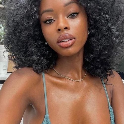 Sapphire Blaze – Busty woman with curly black hair in bikini top posing for phone chat profile