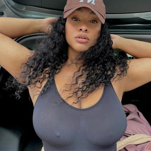 Curvy Afro-Caribbean woman in black tank top posing confidently with hat – Kali Monroe