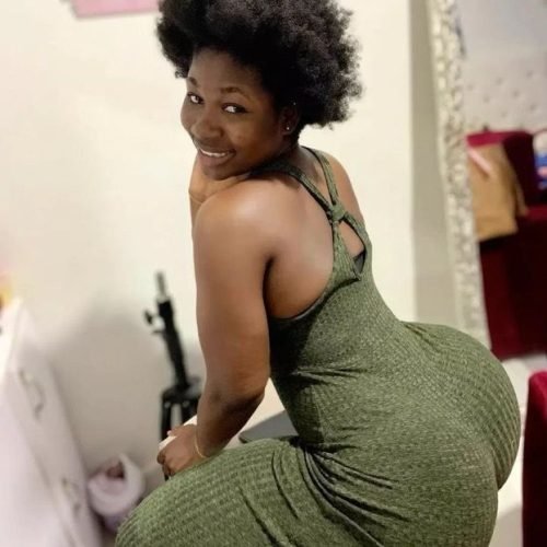 Nyla Noir – Curvy Caribbean woman in green dress smiling seductively over her shoulder in London UK