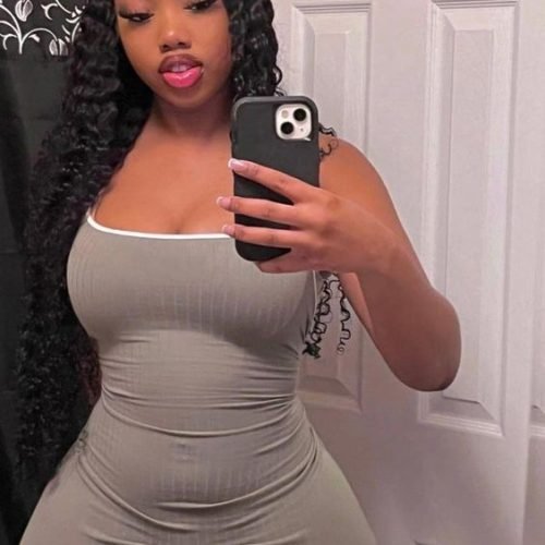 Ebony goddess in fitted grey dress taking mirror selfie
