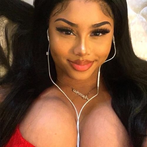 Ebony beauty in red top wearing earphones smiling seductively