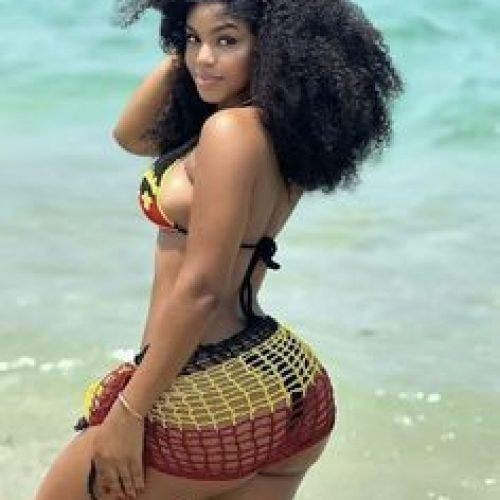 Curvy Caribbean beauty Talia Breeze posing by the ocean in rasta bikini
