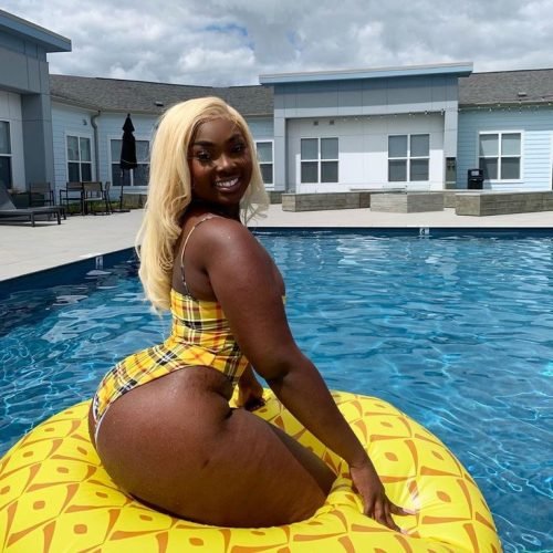 Caribbean Phone Chat Girl in UK Amara Gold – curvy Caribbean woman in yellow bikini sitting on float in pool smiling seductively