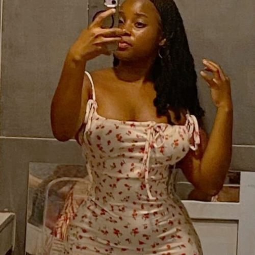 Amara Blake, curvy ebony woman in a tight floral dress taking a mirror selfie