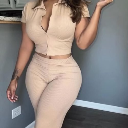 Curvy brunette woman in beige outfit posing with a seductive smile