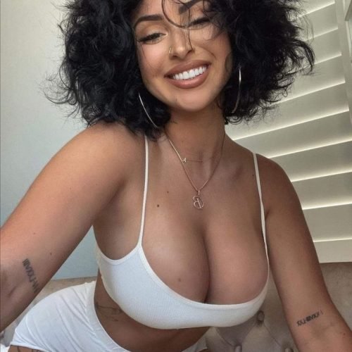 Caribbean woman in white two-piece smiling seductively in London UK
