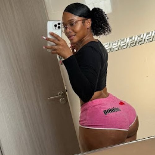 Curvy woman in pink Puma shorts and black crop top taking mirror selfie, turned back pose showing her booty – Nyla Rush, UK adult phone chat tease