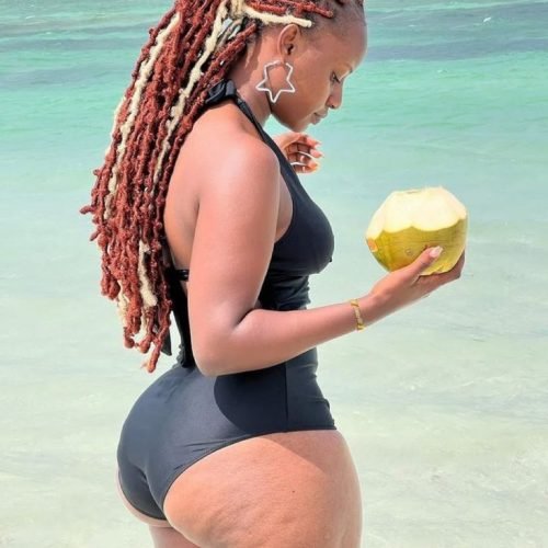 Marisha Dread – Caribbean ebony queen in black swimsuit with coconut by the beach